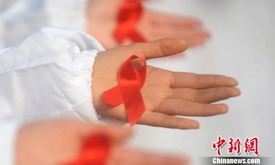 The picture shows college students displaying the red ribbon with the anti-AIDS symbol. Photo by Meng Delong